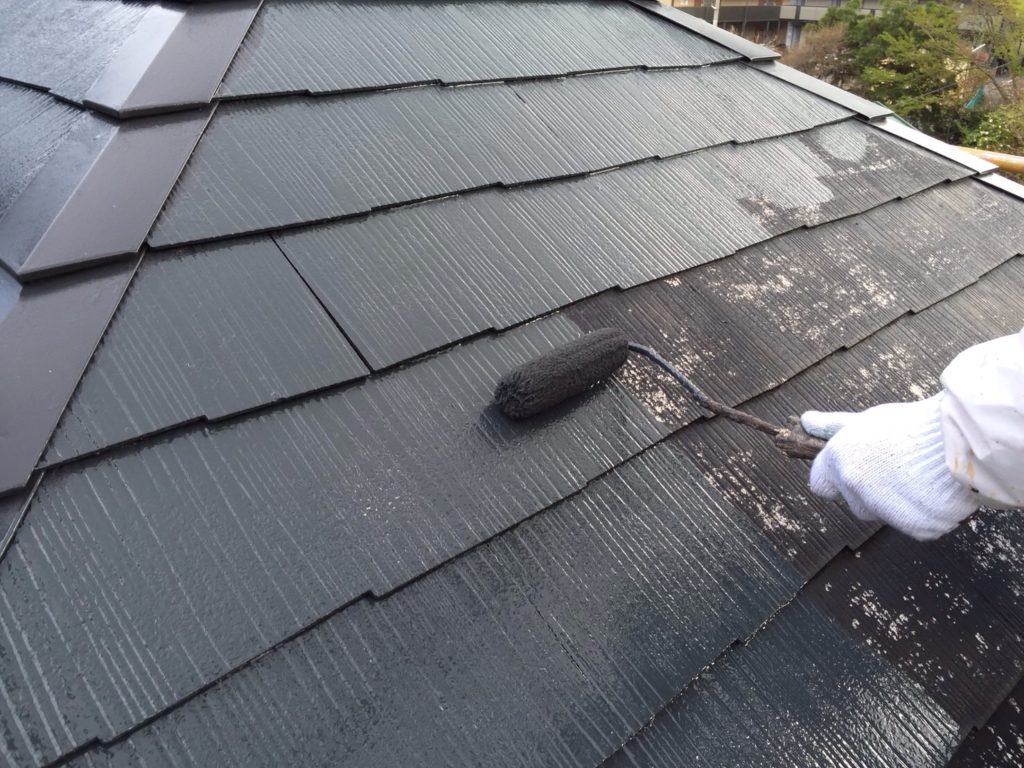 黒の塗料で屋根を塗り上げていく職人